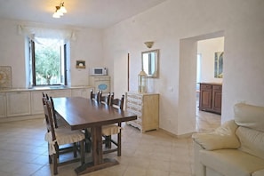 A dining area with a wooden table and chairs, a white cabinet, a microwave, and a mirror on the wall. - Villa del Sognatore, tuscan villa with pool for 12 (Careggia)