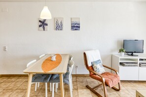 Ein Essbereich mit Tisch, Stühlen, einer Hängelampe und Kunstwerken an der Wand.