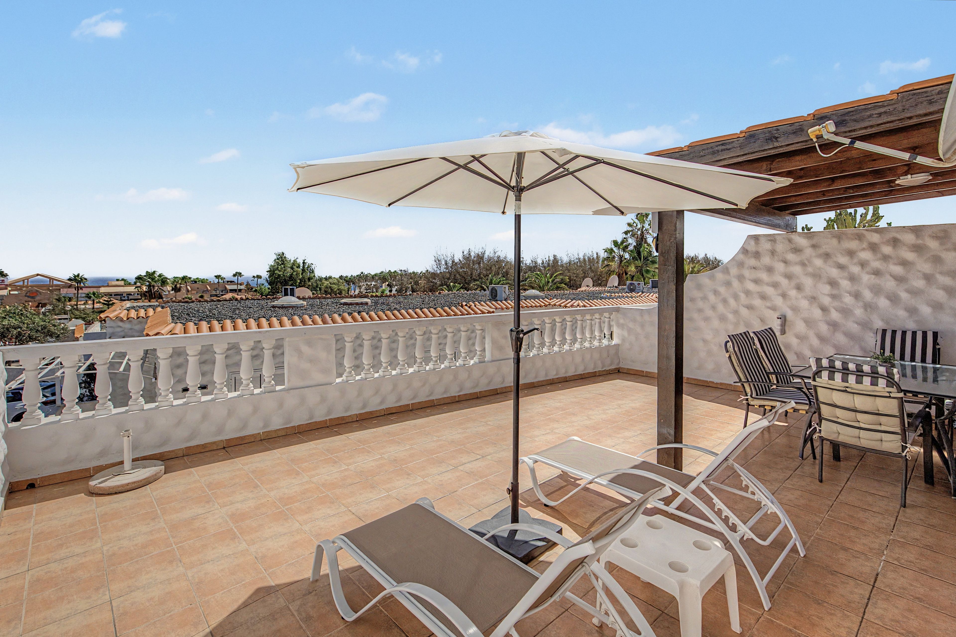 Une terrasse avec une table, des chaises et un parasol.