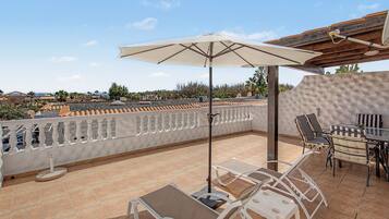 Une terrasse avec une table, des chaises et un parasol.