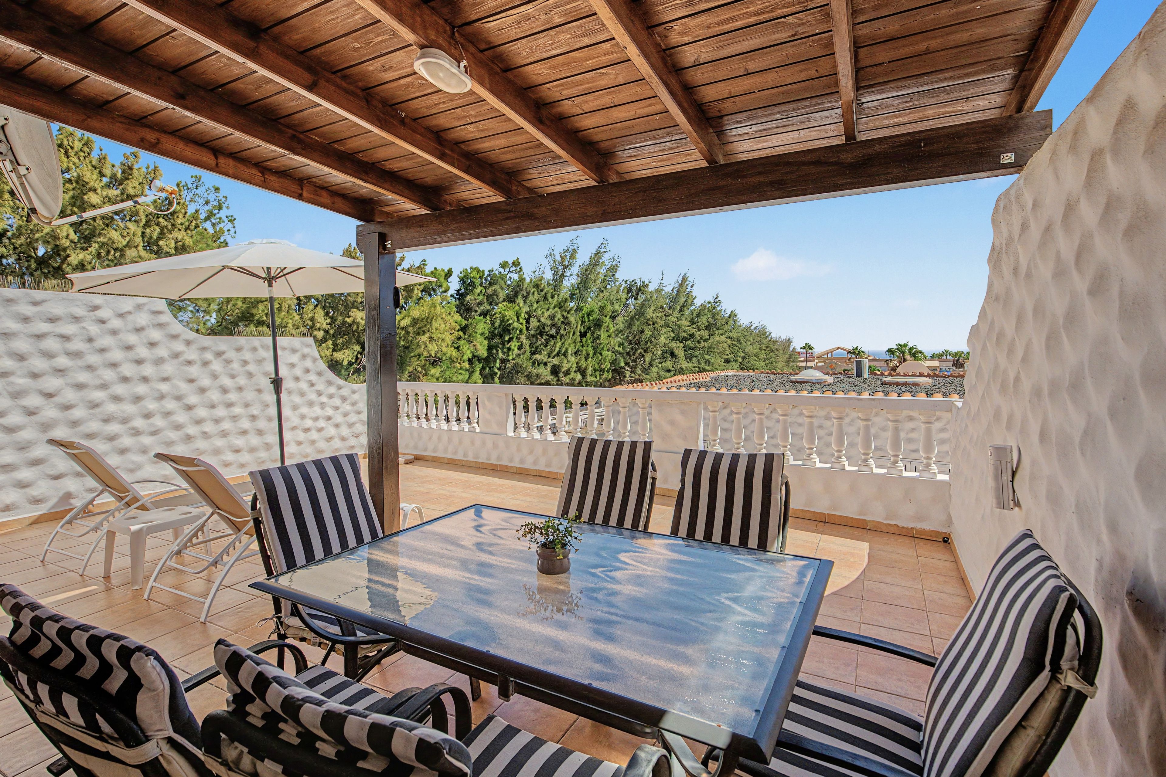 Une terrasse extérieure avec une table et des chaises, un ventilateur de plafond et une vue sur le paysage.