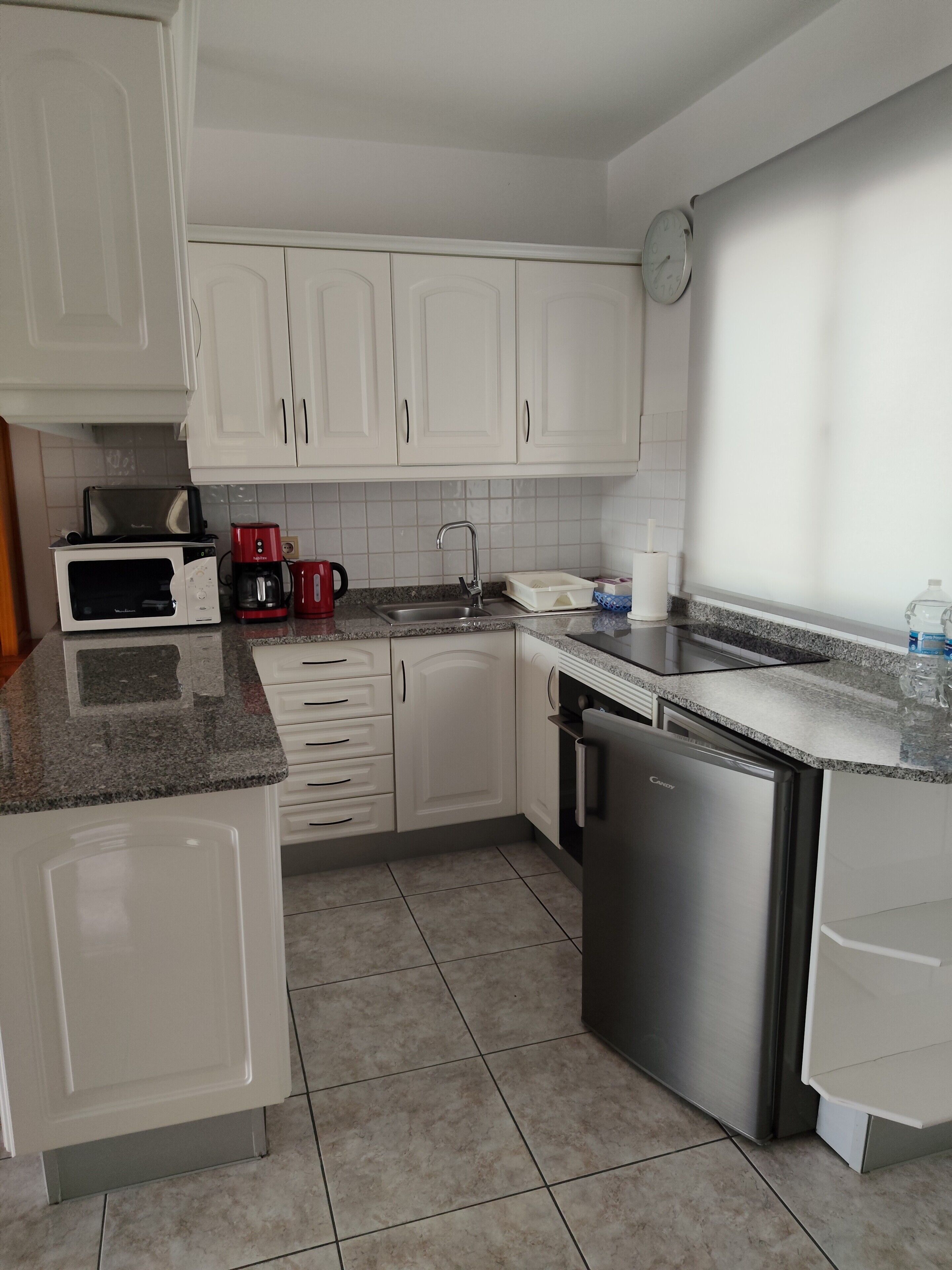 A kitchen with white cabinets, a microwave, a coffee maker, a sink, and a dishwasher.