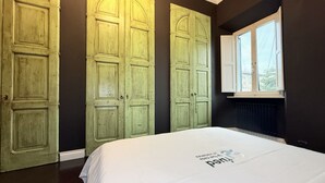 A bedroom with a large bed, two green doors, and a window. - SE248 - Senigallia, three-room apartment in an elegant period building (Senigallia)