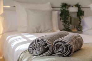 A neatly made bed with rolled towels, a white headboard, and a plant in the background. - Luxury villa Teide View, Pool, Sauna & Golf (Puerto de la Cruz)
