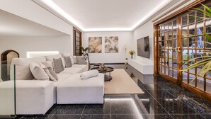A modern living room with a sectional sofa, a coffee table, artwork on the walls, and a large window with a view.