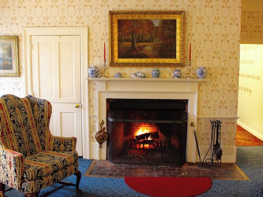 A room with a fireplace, a patterned armchair, and a painting on the wall.