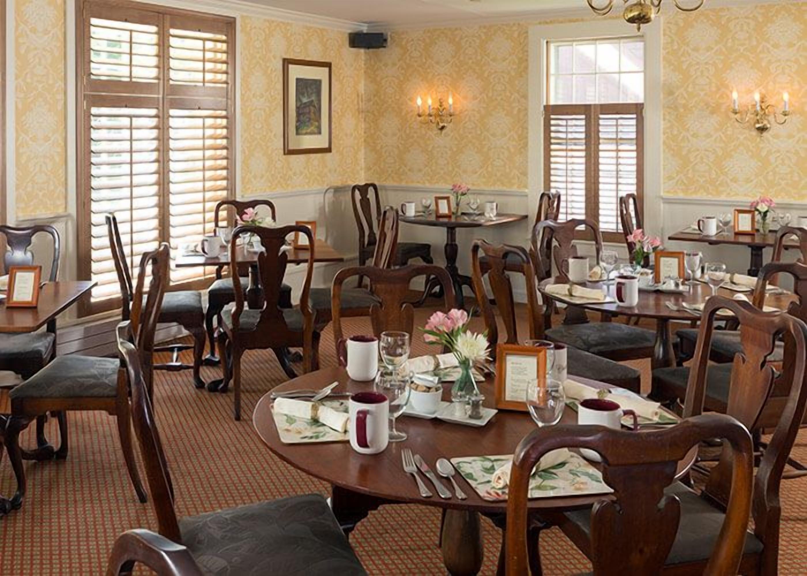 A dining area with round tables, chairs, and a patterned carpet.