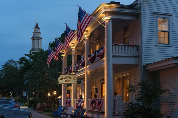 A historic building with a covered porch, American flags, and a sign reading 'Deerfield Inn.' - Deerfield Inn (Deerfield)