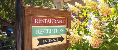 Un letrero de madera que dice 'RESTAURANT RECEPTION ENTRANCE' con una flecha señalando a la derecha.