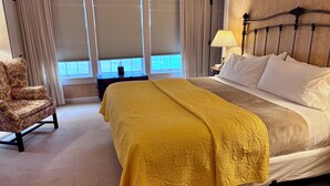 A hotel room with a bed, a chair, a lamp, and a window with curtains. - Deerfield Inn (Deerfield)