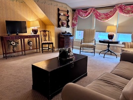 Una sala de estar con televisor, mesa de centro, sofá, sillón y lámpara.