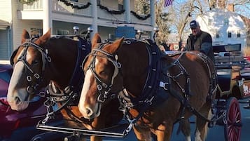 A carriage with two horses in front of a building with a sign that reads 'Deerfield Inn.'