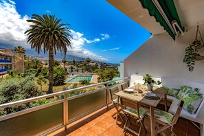 A balcony with a table and chairs, overlooking a pool and greenery. - Luxury terrace with private BBQ N9 (Puerto de la Cruz)