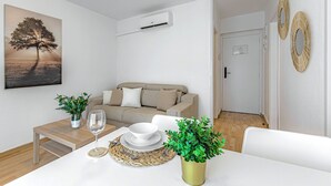 A modern living room with a sofa, a dining table with a glass, a bowl, and a potted plant. - Sea and viewpoint view N3 (Puerto de la Cruz)
