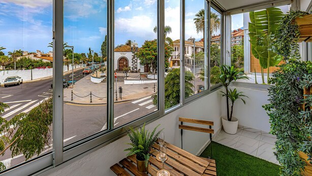 A room with large windows, a bench, a potted plant, and a glass of water. - Sea and viewpoint view N3 (Puerto de la Cruz)