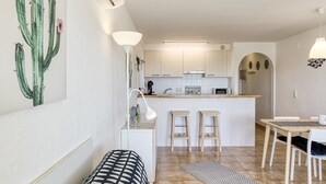 Et moderne køkken med hvide skabe, en central ø og barstole.