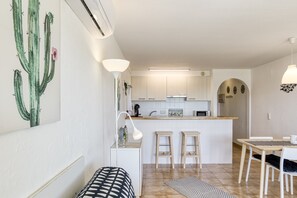 Eine moderne Küche mit weißen Schränken, einer Kochinsel und Barhocker.