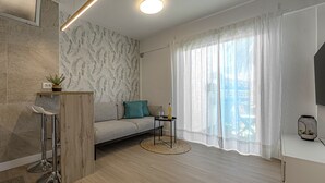 A modern living room with a sofa, a small round table, a TV, and a window with sheer curtains. - Teide and sea view N7 (Puerto de la Cruz)
