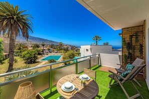 Ein Balkon mit Blick auf einen Swimmingpool, Palmen und entfernte Berge.