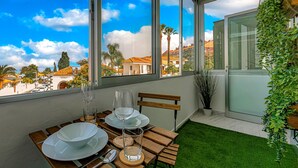 A dining area with a table set for two, large windows, and a view of buildings and palm trees. - Sea and viewpoint view N6 (Puerto de la Cruz)