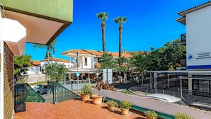 A terrace with tiled flooring, potted plants, and a view of a street with buildings and palm trees. - Sea and viewpoint view N6 (Puerto de la Cruz)