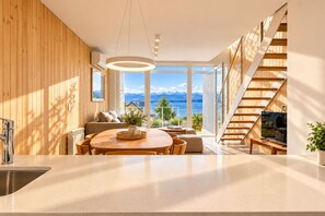 A modern kitchen with a central island, a dining area with a view, and a staircase leading to an upper level. - Signature Lake View, Luxury Residences - Unit B06 (San Carlos de Bariloche)