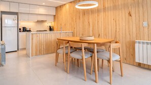 A modern kitchen with wooden paneling, a central island, and a dining area with a table and chairs. - Signature Lake View, Luxury Residences - Unit B06 (San Carlos de Bariloche)