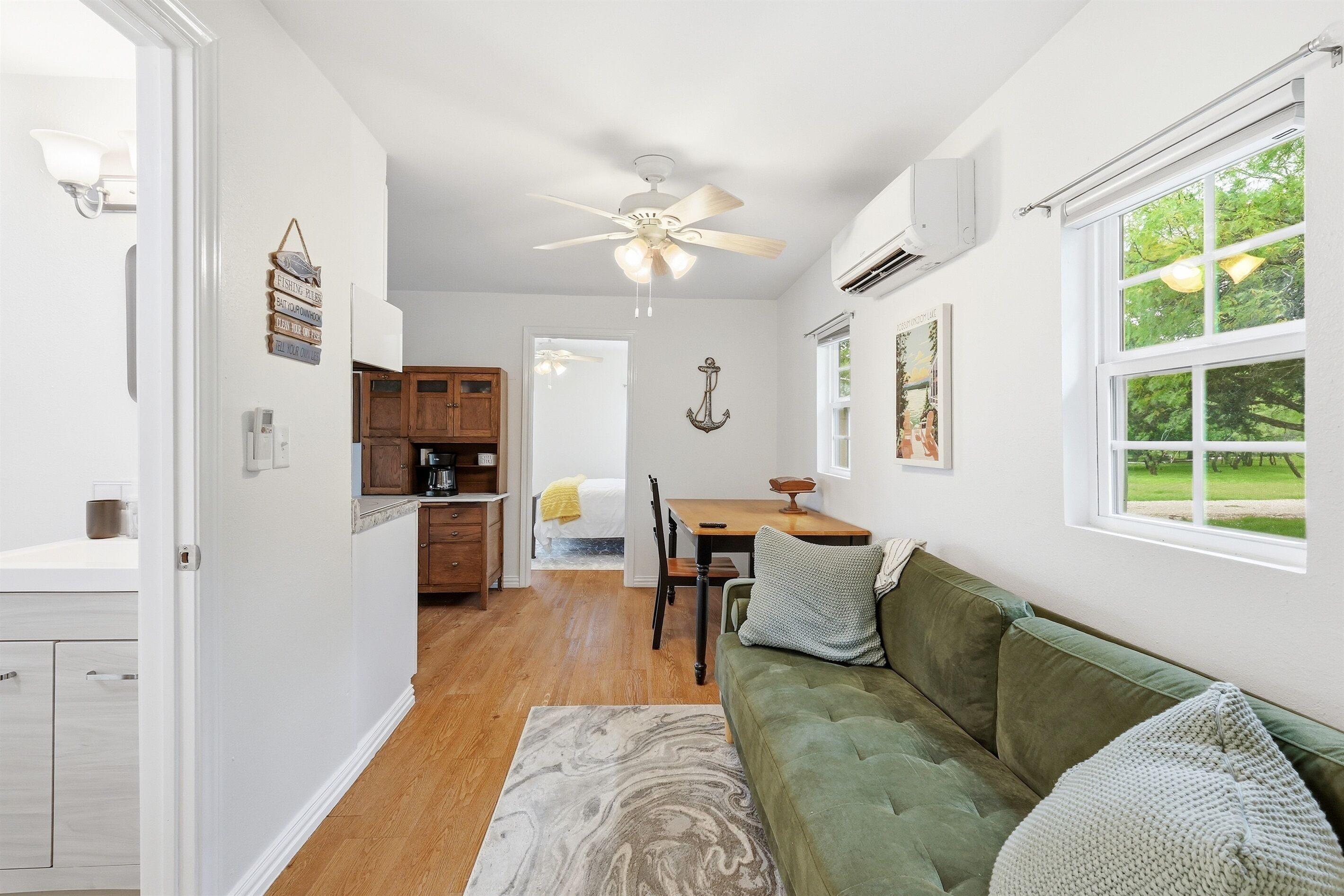 A kitchen with wooden cabinets, a dining table, and a green couch.