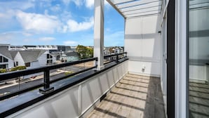 A balcony with a view of residential buildings, a wooden floor, and a white railing. - Luxury 3BR with Seaside Views Jersey Shore Gem (Seaside Heights)