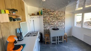 Una cocina con estufa a gas, armarios de madera, pared de ladrillo y una ventana.