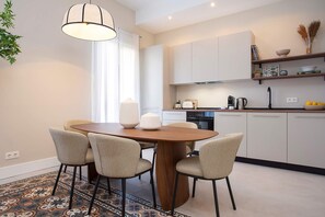 A modern kitchen with white cabinets, a wooden dining table, and four chairs. - Luxurious 3 bd apartment in Granada. San Anton 302 (Granada)