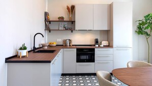 Eine moderne Küche mit weißen Schränken, einer Holzarbeitsplatte, einem eingebauten Backofen und einem Essbereich mit rundem Tisch und Stühlen.