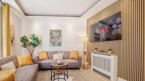 Un salon moderne avec un canapé, une table basse et un téléviseur fixé à un mur en bois.