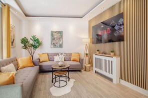 Ein modernes Wohnzimmer mit einer Couch, einem Couchtisch und einem an einer Holzwand montierten Fernseher.