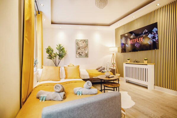 Ein Hotelzimmer mit einem Bett, einem Fernseher, einer Pflanze und einem Schreibtisch mit einer Lampe.