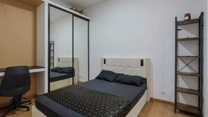 Ett sovrum med en säng, ett skrivbord, en stol, en garderob och en hylla.