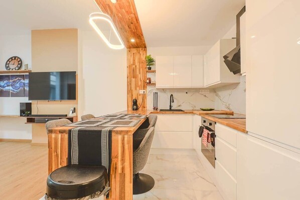 A modern kitchen with a wooden island, white cabinetry, and a built-in oven. - Comfortable apartment on the Cours Julien (Marseille)