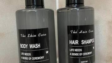 Due flaconi di bagnoschiuma e shampoo per capelli su una superficie piastrellata.