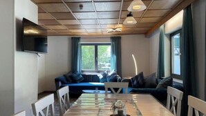 Un comedor con una mesa de madera, sillas, una cafetera y un sofá con cojines.