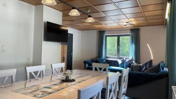 Un comedor con una mesa, sillas y un televisor montado en la pared.