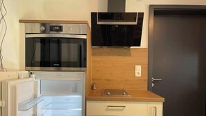 Una cocina compacta con horno integrado, microondas y encimera de madera.