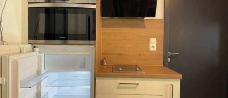 A compact kitchen with a built-in oven, microwave, and a wooden countertop.