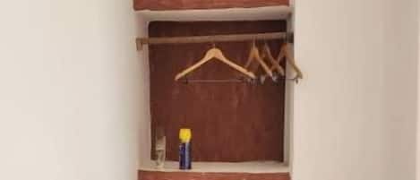 Un pasillo estrecho con un armario de madera que contiene estantes y una barra para colgar ropa.