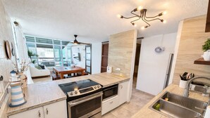 Een moderne keuken met een inbouwoven, een eethoek met een houten tafel en uitzicht op de omgeving.