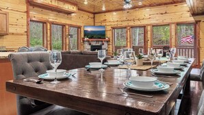 Un intérieur en bois comprenant une table à manger pour six personnes, une cheminée et un téléviseur.