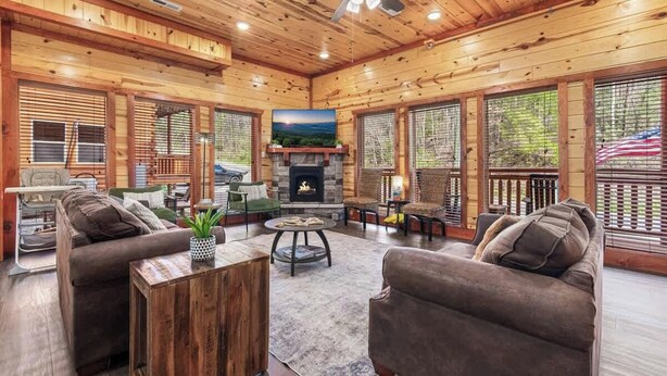 Un salon spacieux doté d’une cheminée, de murs en bois et de grandes fenêtres.