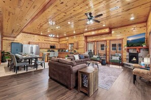 Ein geräumiges Blockhütten-Interieur mit Essbereich, einer Couch, einem Kamin und einer Küche.