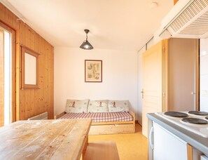 Una cocina compacta con una mesa de madera, un banco con cojines, una lámpara colgante y una estufa.