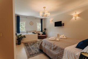 Une chambre à coucher avec un lit, un lustre, un téléviseur fixé au mur et une plante en pot.