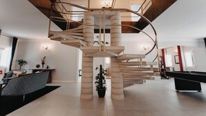 Ein modernes Interieur mit einer Wendeltreppe, einem Billardtisch und einer Sitzecke.